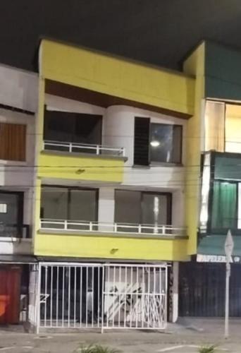 a yellow and white apartment building with a balcony at colibrí Hostel in Armenia