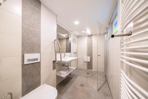 a white bathroom with a sink and a toilet at Chalets Camping Brunner am See in Döbriach