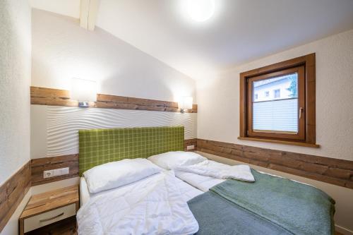 a bedroom with a bed with a green headboard and a window at Chalets Camping Brunner am See in Döbriach