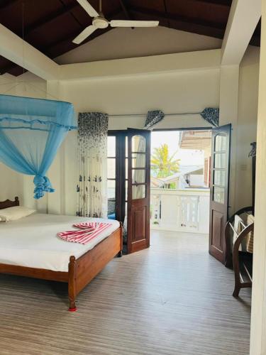 a bedroom with a bed and a large window at Traveler's Cottage in Unawatuna