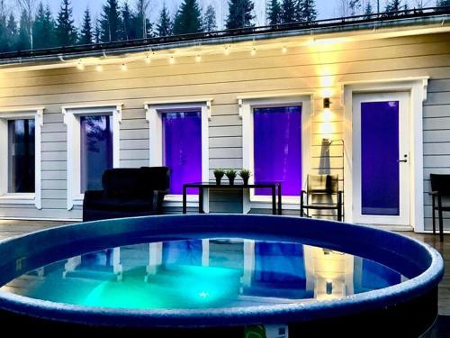 a large pool in front of a house with purple doors at Villa Renkaranta - Modern villa for 8-12 person, own beach, sauna & hot tub - surrounded by forests in Hämeenlinna