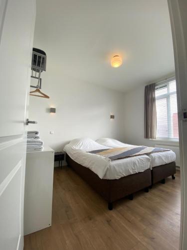 a bedroom with a bed and a white wall at NEW Appartment Zandvoort! in Zandvoort