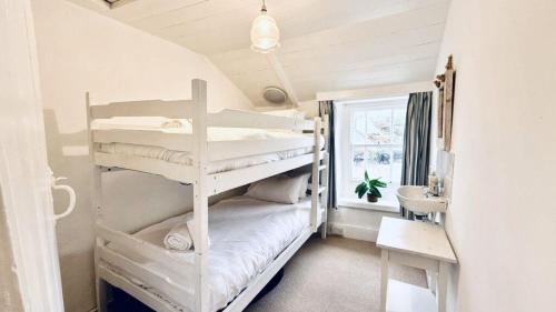 a bedroom with two bunk beds and a sink at Waves End - Port Isaac Cornwall in Port Isaac