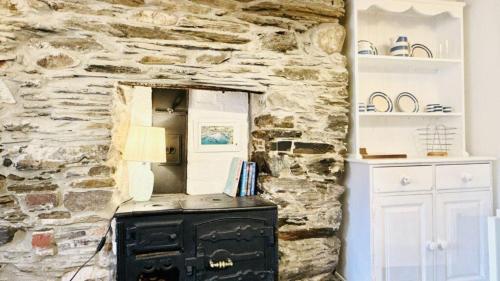 a stone wall with a black stove in a room at Waves End - Port Isaac Cornwall in Port Isaac