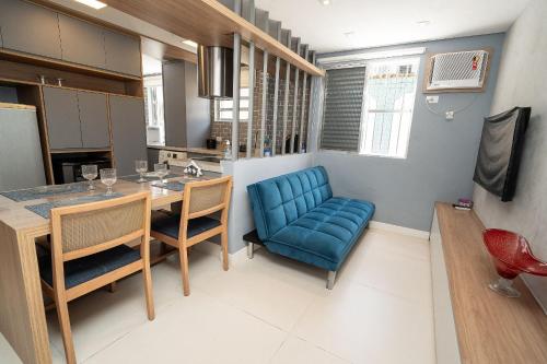 a kitchen with a blue couch and a table and chairs at Seu apê de férias - Praia Grande in Praia Grande