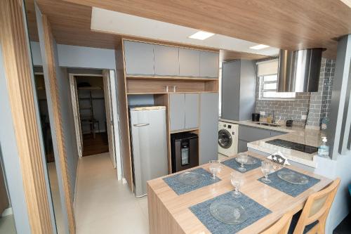 a kitchen with a wooden table and a refrigerator at Seu apê de férias - Praia Grande in Praia Grande