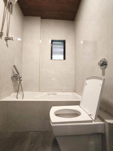 a white bathroom with a toilet and a bath tub at Sai Paradise lodging and Boarding in Dombivli