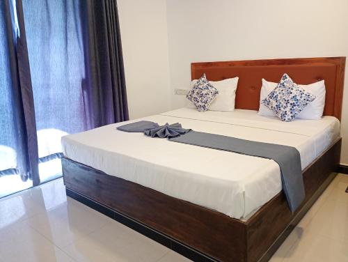 a bedroom with a large bed with white and blue pillows at Amelia resort in Udawalayagama