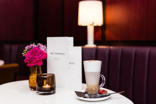 a table with a cup of coffee and a vase of flowers at The Rockwell in London