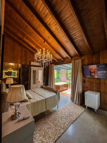 a bedroom with a large bed and a chandelier at WoodStone Hotel Fazenda in Gramado