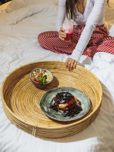 Una donna seduta su un letto con un piatto di cibo di Niki Athens Hotel ad Atene