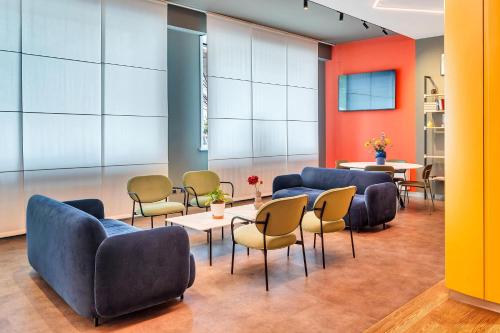 una sala d'attesa con divani, sedie e tavoli di B&B Hotel Milano Aosta a Milano