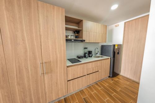 a kitchen with wooden cabinets and a refrigerator at Modern studio apartment with AC and secure parking in Acacías
