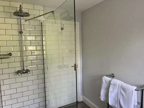 bagno con doccia in vetro e piastrelle bianche di The Priory Cottage a Legbourne