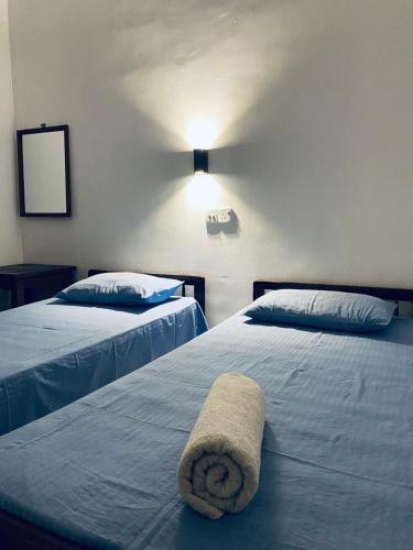 a hotel room with two beds with a towel on them at Chandra Holiday Home Hiriketiya in Dickwella