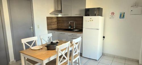 a kitchen with a table and a white refrigerator at La Proue T2 étoilé in Saint-Méloir-des-Ondes