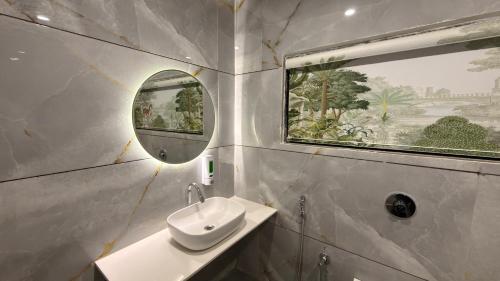 a bathroom with a sink and a mirror and a window at Hotel Radhe in Junagadh
