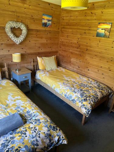 twee bedden in een kamer met houten wanden bij Willow Valley in Bude