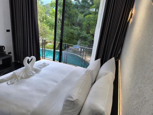 a bedroom with a white bed with a large window at Khanom Station 549 in Ban Na Dan