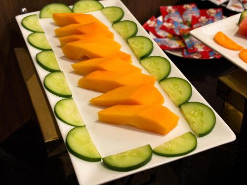 ニューデリーにあるHotel cardinal Express Oxmo Near IGI Delhi Airportのチーズとキュウリのスライスを乗せた白い皿