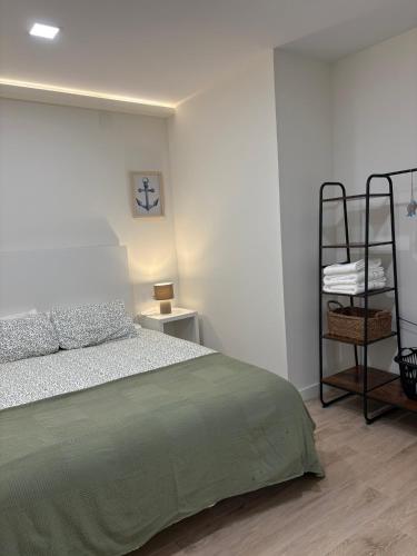a white bedroom with a bed and a shelf at Arena - El Silencio Apartamentos in Castañeras