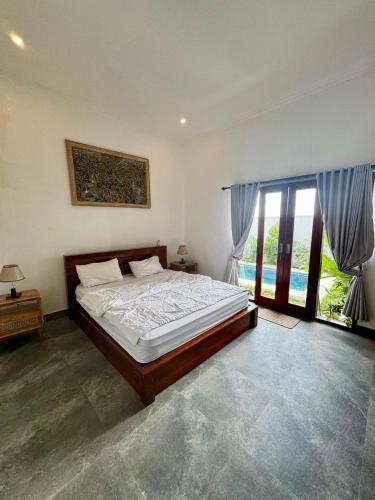 a bedroom with a bed and a large window at Elegant Jaden Villa Cemagi in Mengwi