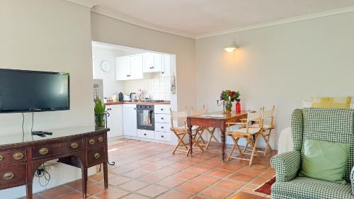 a living room with a television and a table with chairs at Cruise Cottage in Stanford