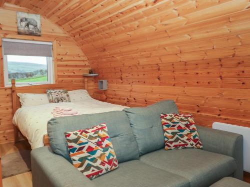 a room with a couch and a bed in a log cabin at Willow in Ulverston
