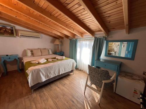 a bedroom with a bed and a chair and a window at Bedirhan Konak Otel in Alaçatı