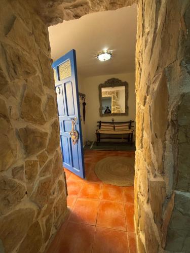 a hallway with a blue door and a stone wall at Cueva Colorin Alloza. in Alloza