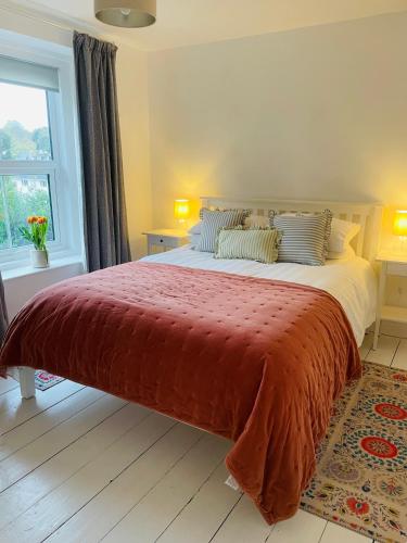 a bedroom with a large bed with a red blanket at Dartmoor Cottage in Bovey Tracey
