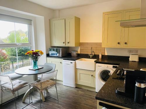 a kitchen with a table with a vase of flowers on it at Dartmoor Cottage in Bovey Tracey