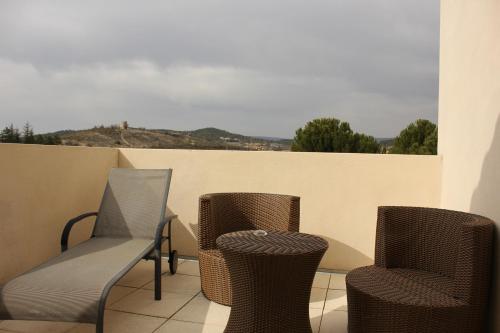 three chairs and a table on a balcony at Logis Hôtel Le Manoir & Lounge in Apt