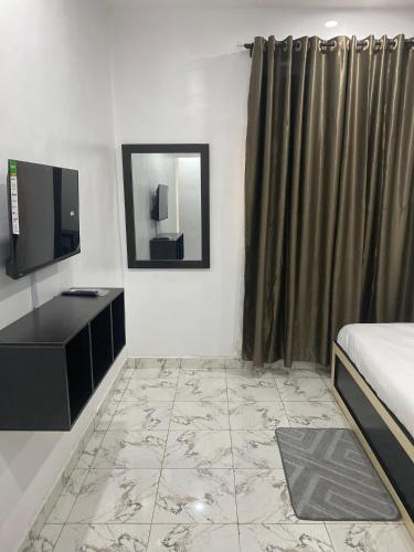 a bedroom with a bed and a tv and a mirror at Adonai Guesthouse in Agbara