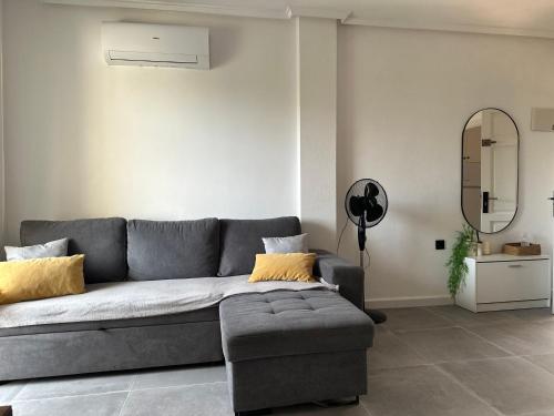 Sala de estar con sofá gris y espejo en PARQUE AROMATICO CON DOS PISCINAS, en Torrevieja