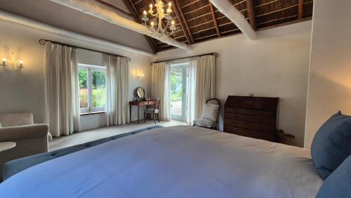 a bedroom with a large bed and a chair and windows at Coppull Private Nature Reserve in Stanford
