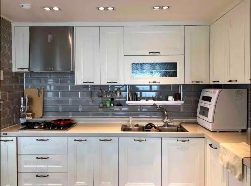 a kitchen with white cabinets and a sink and a microwave at 여성전용1인숙소 Milli Home 