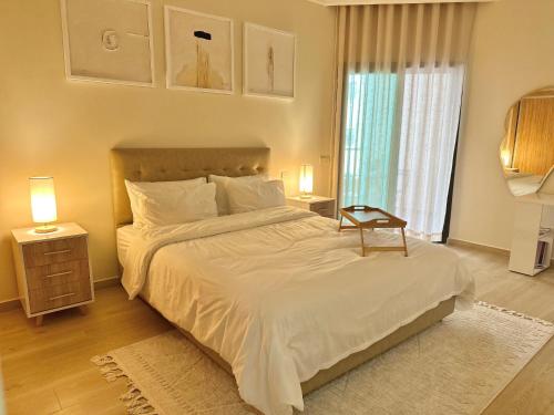 a bedroom with a bed with white sheets and a window at Modern Comfort Studio, la corniche in Mohammedia