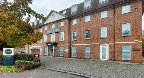 a large red brick building with a sign on it at B&B HOTEL London Heathrow in Slough