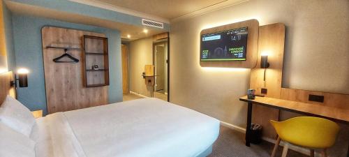 a bedroom with a bed and a tv on the wall at B&B HOTEL London Heathrow in Slough