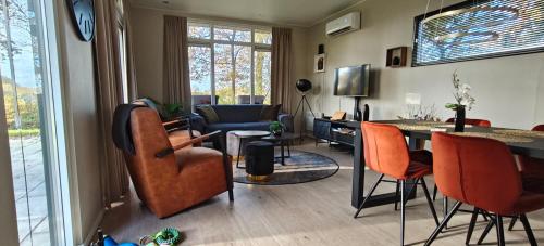 a living room with orange chairs and a table at Casa Kwispel - Hondvriendelijk, luxe, natuur, omheinde tuin in Haarle