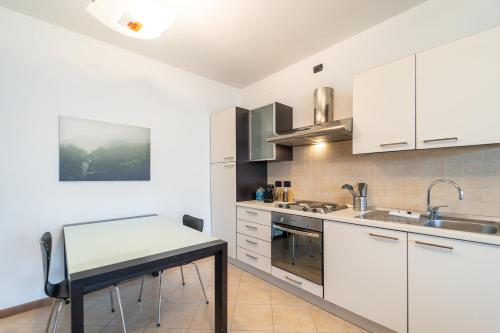 Una cocina con gabinetes blancos y una mesa. en Moderno appartamento con garage, Wi-Fi, aria condizionata e terrazzo, en Milán