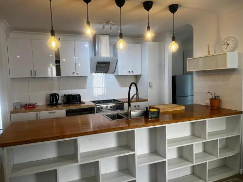 a kitchen with white cabinets and a wooden counter top at 3 bedroom Kids friendly home in Perth