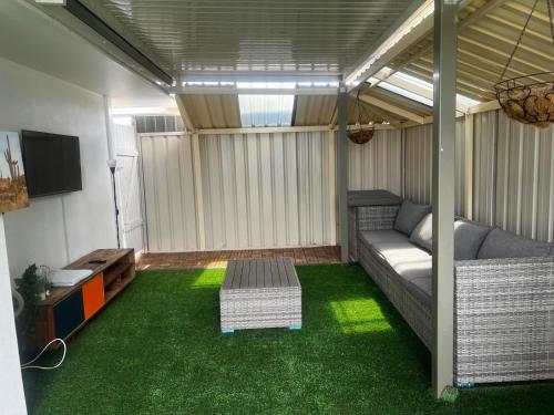 a living room with a couch and green grass at 3 bedroom Kids friendly home in Perth