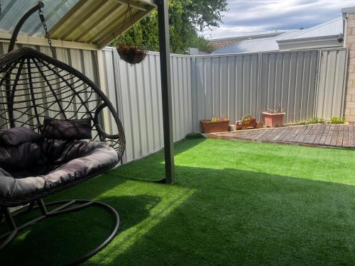 a garden with a chair on the grass at 3 bedroom Kids friendly home in Perth