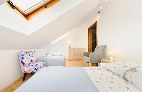 a white bedroom with a bed and a chair at Apartament Milena in Polanica-Zdrój