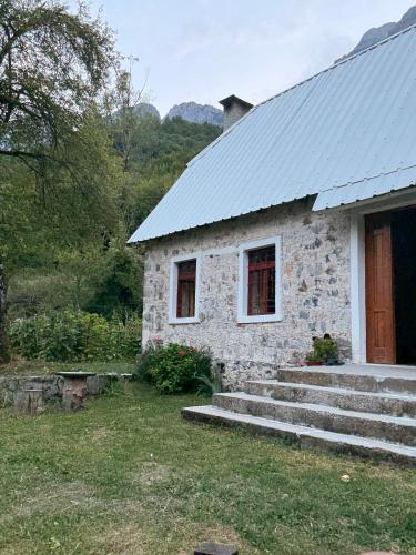 a stone house with a porch and a door at Kulla e Gjyshit - Guest House in Theth