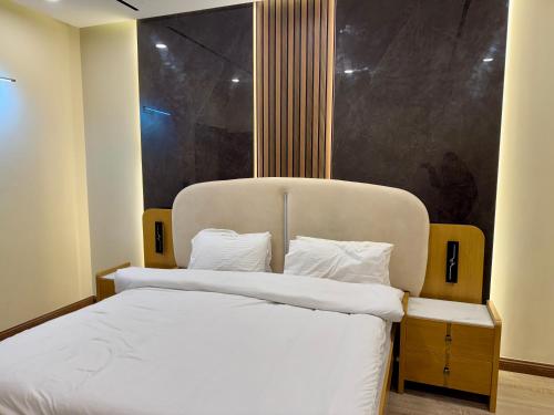 een slaapkamer met een groot bed met witte lakens bij Executive 2BHK in Zeta Mall in Islamabad