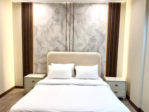 a bedroom with a white bed with a marble wall at Executive 2BHK in Zeta Mall in Islamabad