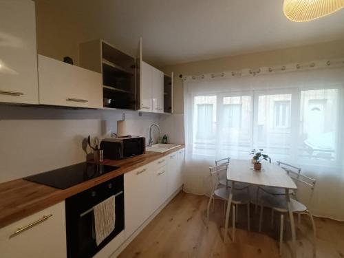 una cucina con mobili bianchi e un tavolo con sedie di L instant carcassonnais a Carcassonne